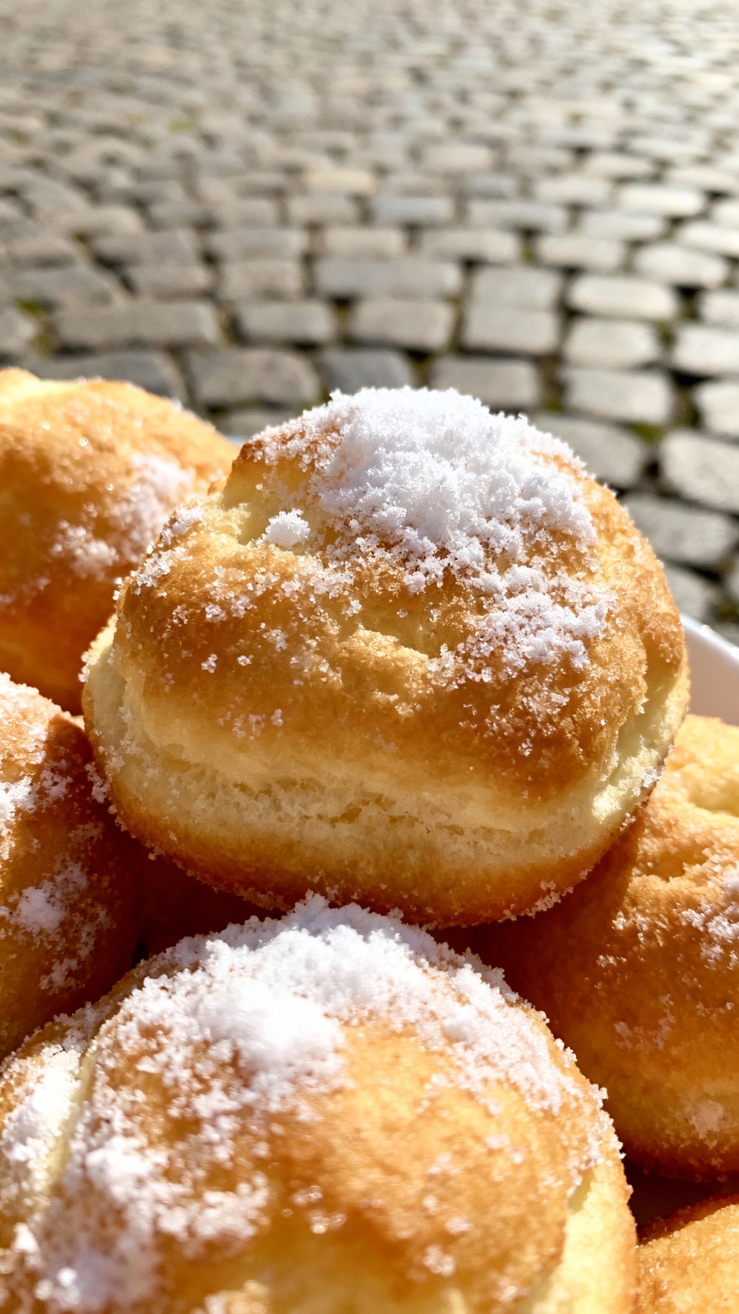 Closeup of Schneeballen pastry dusted with sugar, cobblestone background